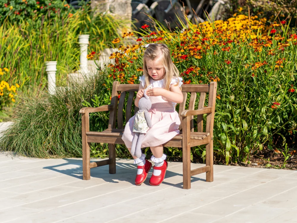 Alexander Rose Broadfield Chestnut Acacia Children's Bench Young child is sat playing on bench High Quality Hardwood Bench